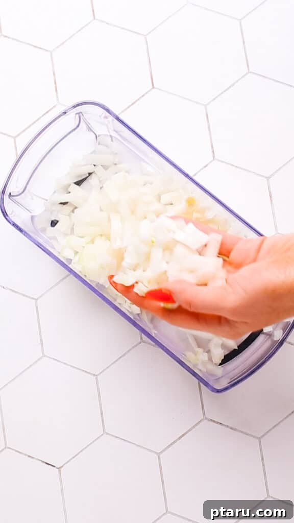 Creamy Butter Paneer 6 Finely diced onions in a food chopper, ready for cooking.