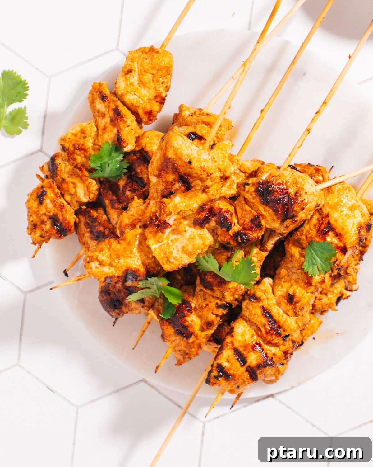The Best Chicken Tikka Recipe For Grill Oven Or Air Fryer 2 Perfectly cooked Chicken Tikka skewers, garnished with fresh cilantro and lime wedges.