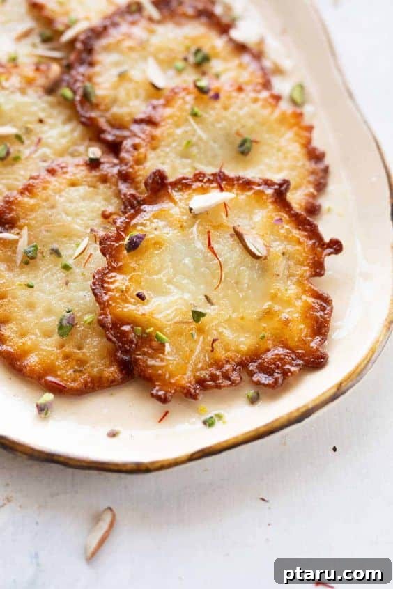 Easy Indian Desserts and Sweets: Crowd-Pleasing Showstoppers 12 Golden-fried Malpua pancakes, drizzled with sugar syrup and garnished, a festive Indian dessert.