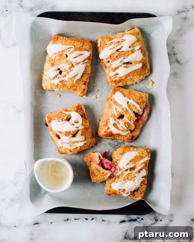 Favorite Easy Rhubarb Recipes You'll Make Forever 15 Golden brown Rhubarb hand pies arranged on a baking tray.