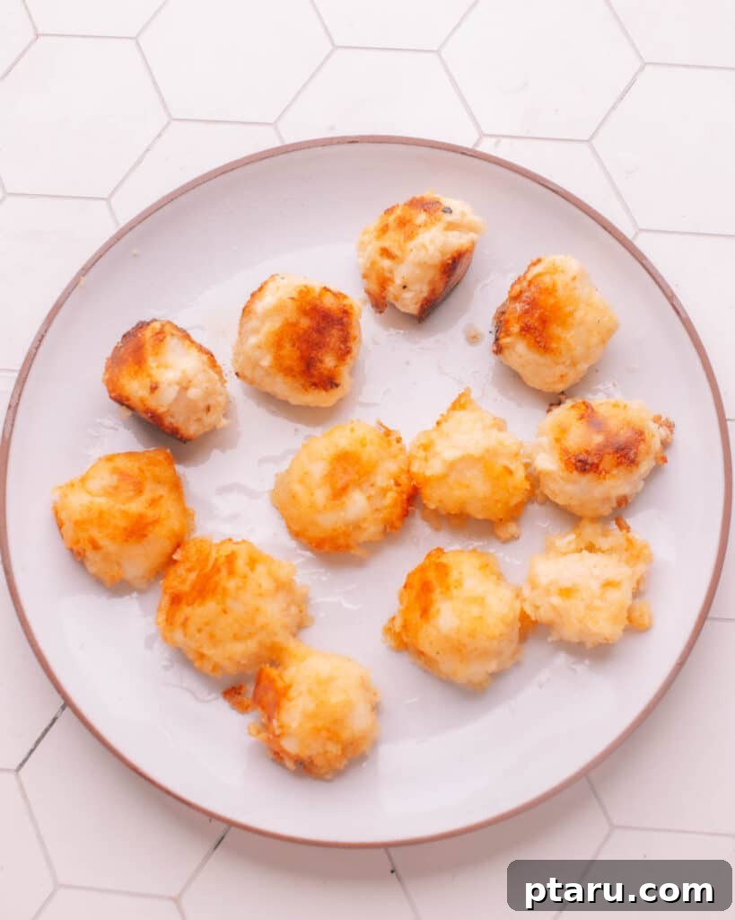 Simple Creamy Paneer Malai Kofta Curry 16 Crispy, golden-fried kofta balls resting on a plate lined with paper towels.
