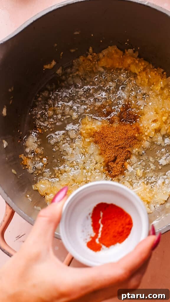 Simple Creamy Paneer Malai Kofta Curry 8 Adding dry spices like cumin and coriander to the onion, garlic, and ginger mixture in the pan.