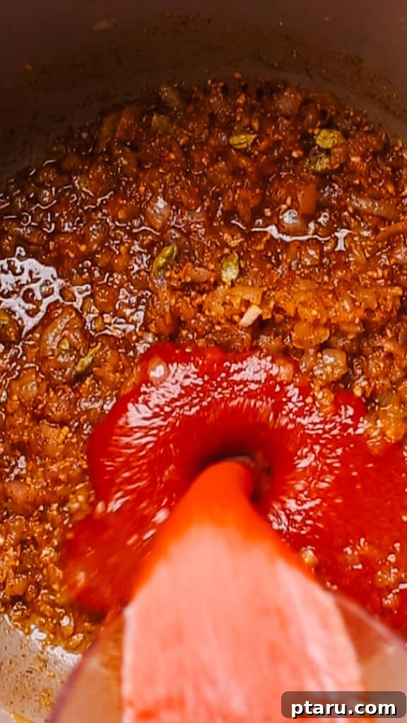 Simple Creamy Paneer Malai Kofta Curry 9 Pouring tomato puree into the spiced onion mixture for the Malai Kofta sauce.