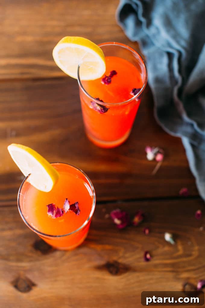 Pink Petal Lemonade 4 Rose lemonade in a glass, with pink rose petals scattered on a table for garnish