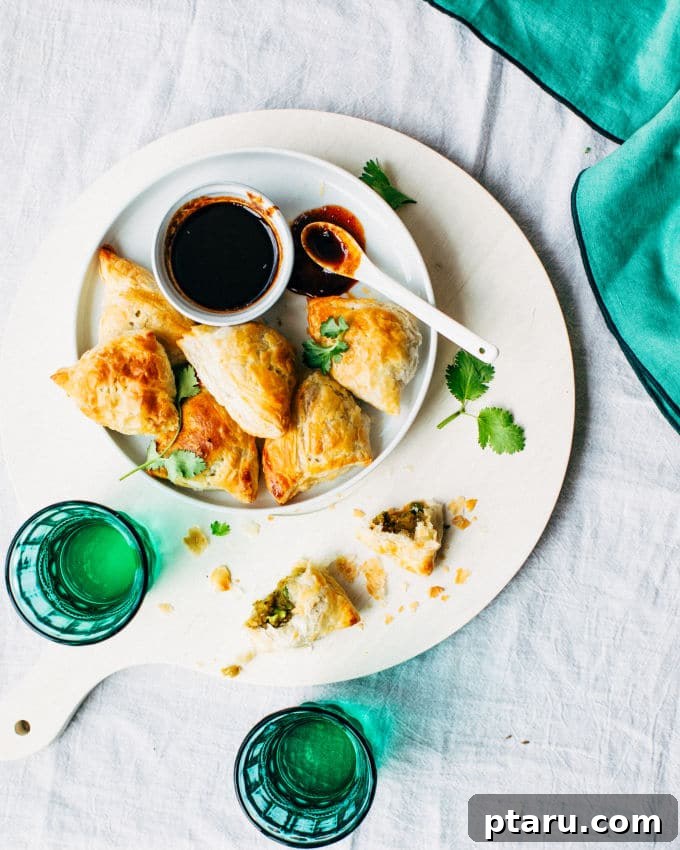 Effortless Flaky Samosas 5 Golden, crispy puff pastry samosas arranged on a baking sheet, fresh out of the oven