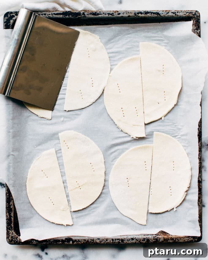 Effortless Flaky Samosas 7 Cutting puff pastry circles in half and pricking them before filling