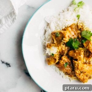 Vindaloo Pork Curry on a plate with rice, garnished with fresh cilantro.