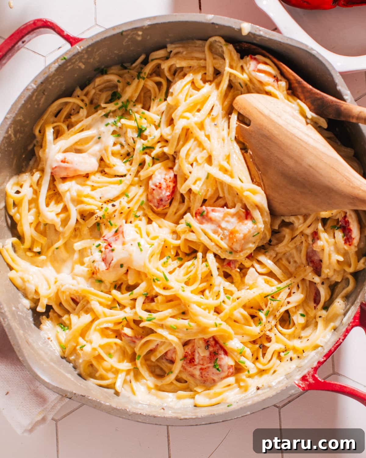 Decadent Lobster Pasta with White Wine Cream 8 Finished Lobster Pasta Recipe in a pan with a serving spoon, garnished with fresh herbs.