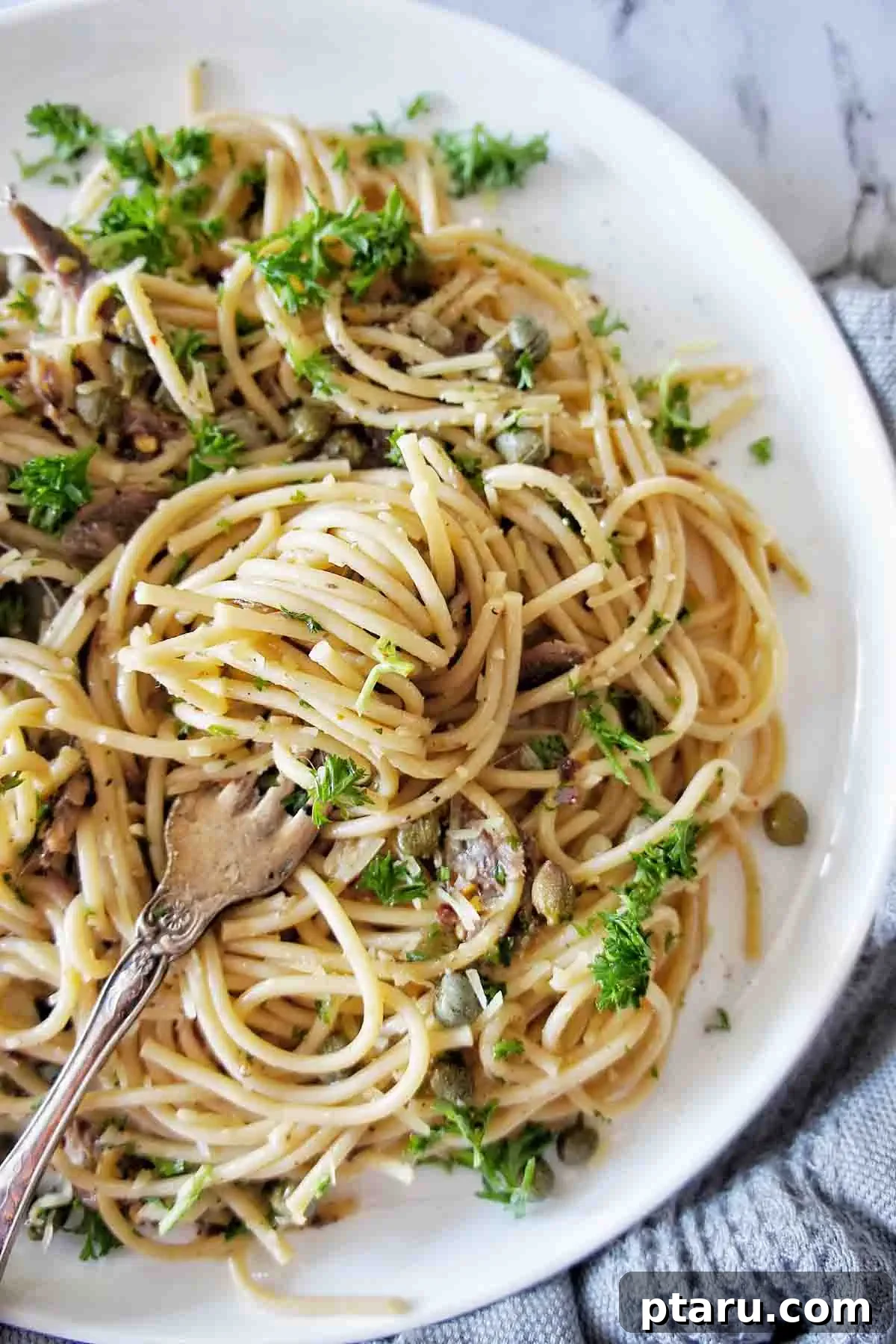 Beyond Basic The Webs Most Unique Pasta Creations 22 Anchovy spaghetti adorned with fresh parsley, chili flakes, and a vibrant sauce.