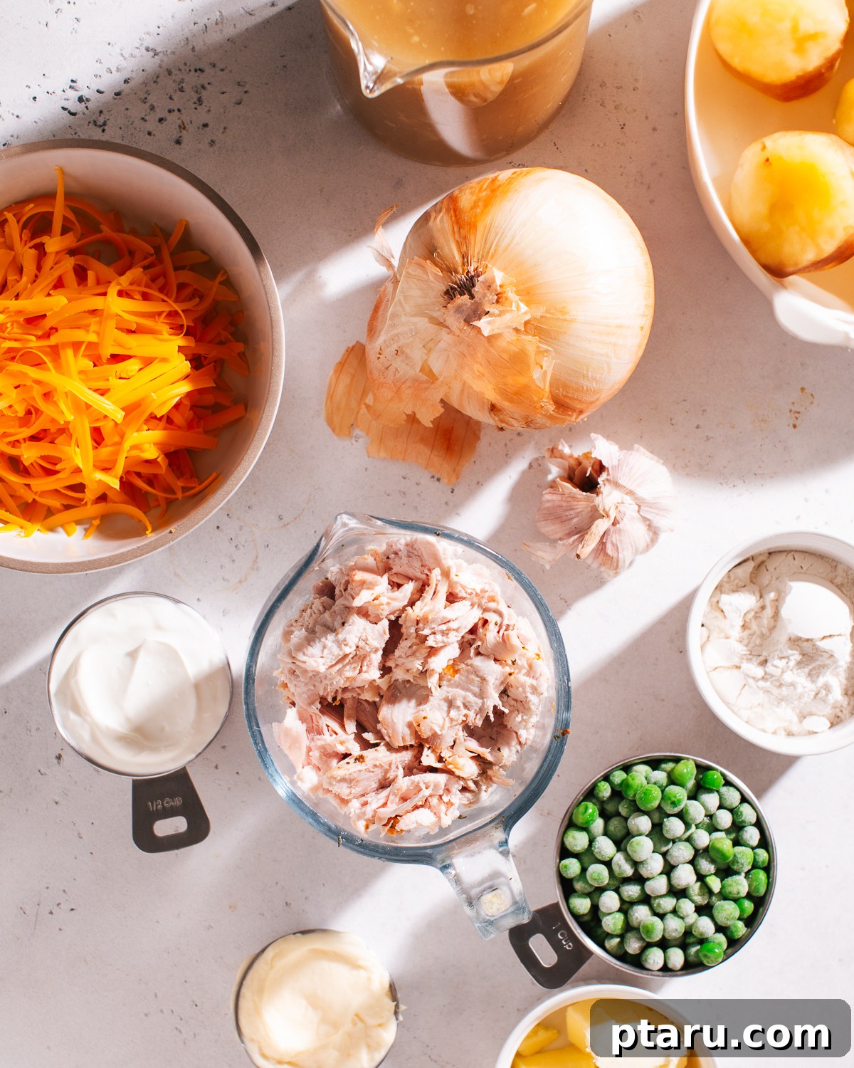 Simply Delicious Chicken Potato Casserole 3 Fresh ingredients laid out on a counter for making Chicken Potato Casserole: potatoes, chicken, cheese, sour cream, mayonnaise, peas, butter, onion, and garlic.