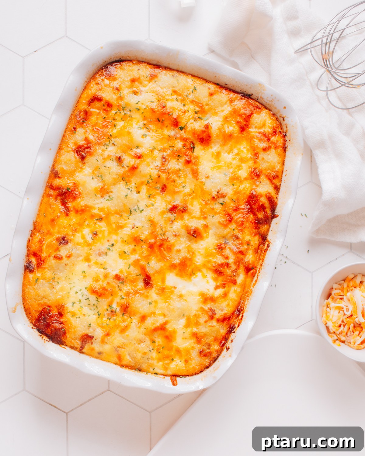 Simply Delicious Chicken Potato Casserole 6 A serving spoon lifting a portion of cheesy, creamy Chicken Potato Casserole from a baking dish.