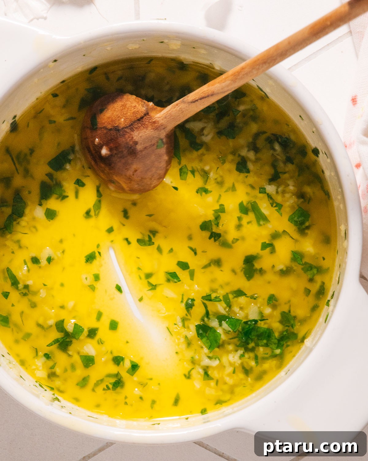 Speedy Three Ingredient Garlic Butter 5 Garlic butter sauce simmering gently in a small pot with a spoon resting inside.