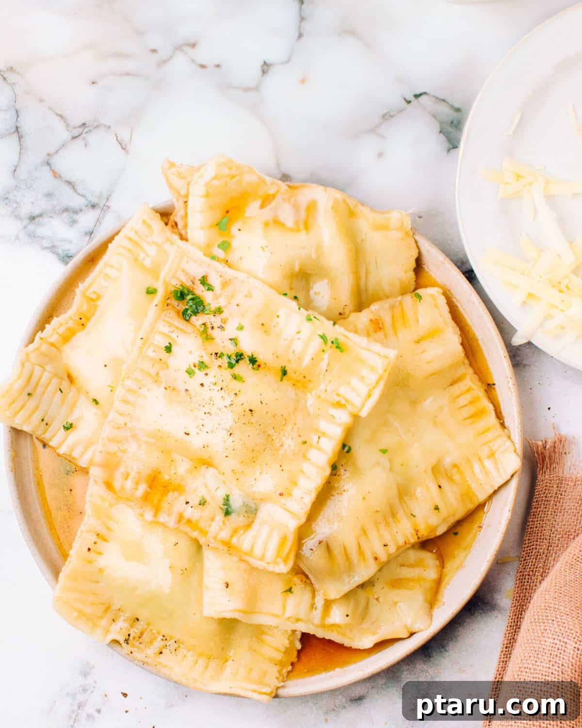 Speedy Three Ingredient Garlic Butter 6 Garlic butter sauce coating a plate of ravioli pasta, garnished with fresh herbs.