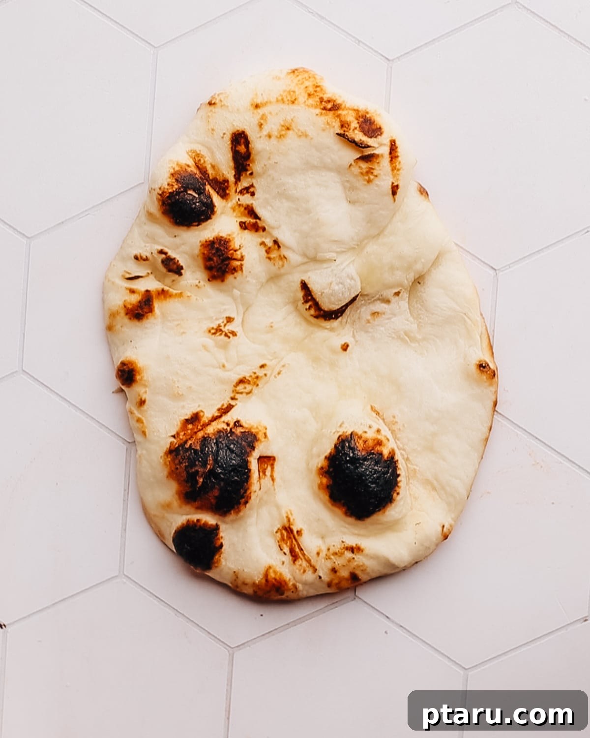 Quick and Easy Naan Pizza in 15 Minutes 5 Fresh naan bread laid out on a clean countertop, ready for pizza assembly.