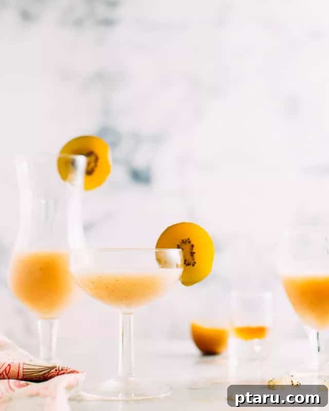 Golden Kiwi Bourbon Sour 2 Two golden kiwi cocktails garnished with kiwi slices, sparkling and inviting.