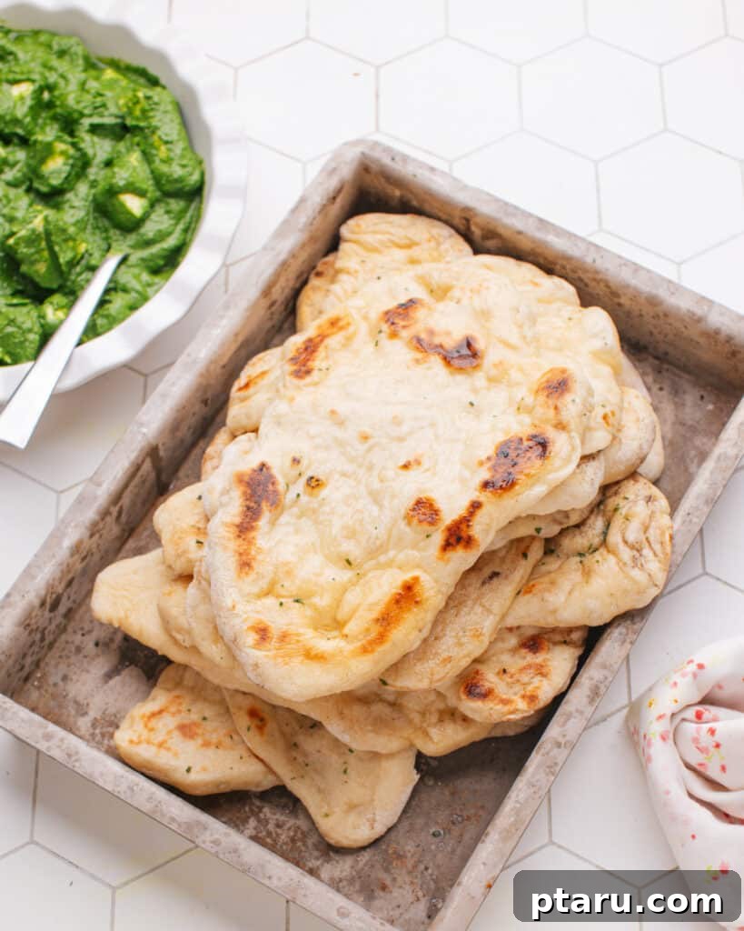 Unbelievably Soft Stretchy Garlic Naan 9 A serving of freshly made homemade Garlic Naan presented alongside a bowl of rich and creamy Palak Paneer, a classic Indian vegetarian dish.