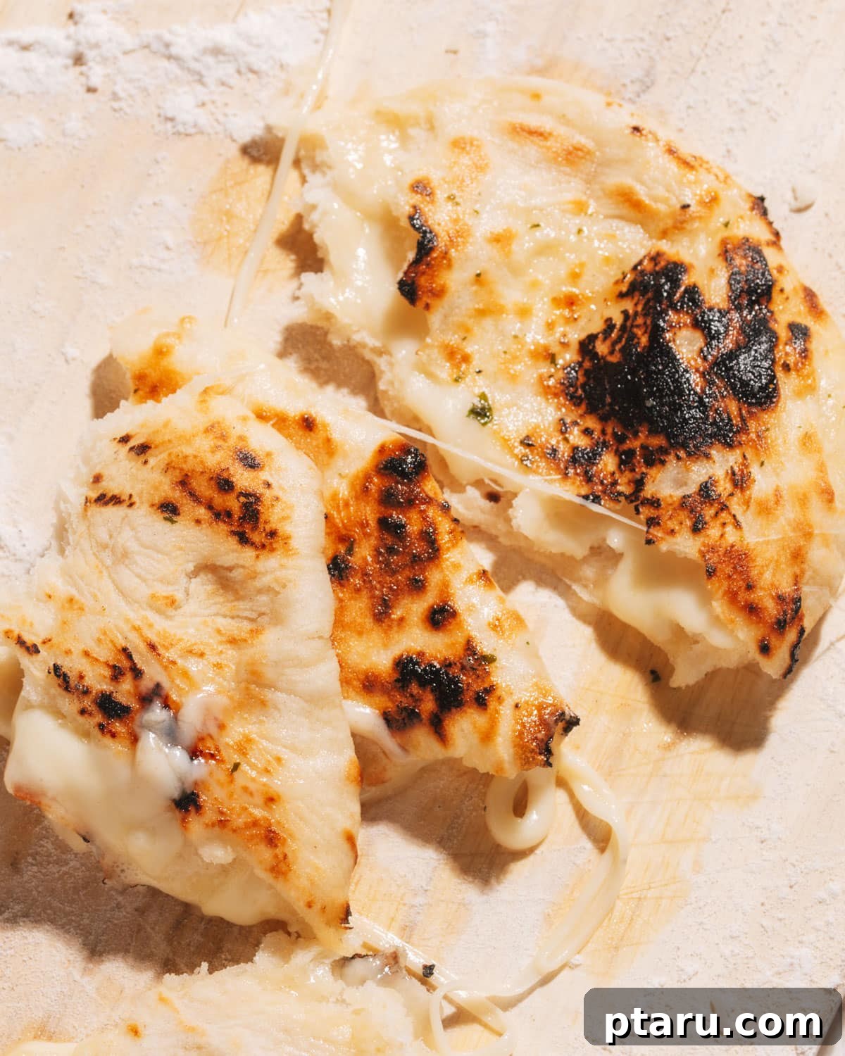 Gooey Cheese Naan 2 Cheese naan on a cutting board with cheese melting out.
