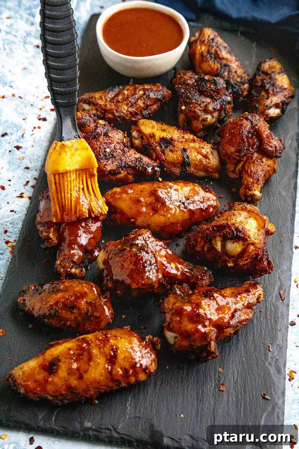 Grilled Wings Perfected 10 Crispy Recipes 3 Vibrantly glazed Honey Sriracha chicken wings on a plate.