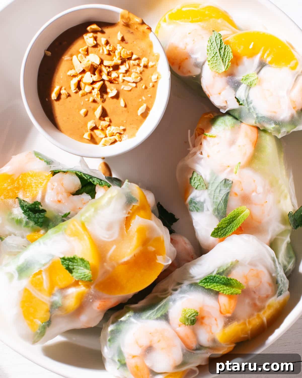 20+ Guilt-Free Shrimp Recipes for Dinner: Absolutely Delicious! 11 Spring rolls on a plate with peanut sauce, garnished with fresh herbs.
