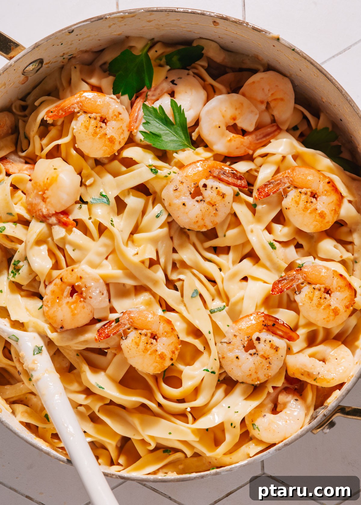 Zesty Lemon Cream Shrimp Pasta 2 Shrimp pasta in a large saucepan with a spoon, garnished with fresh herbs.