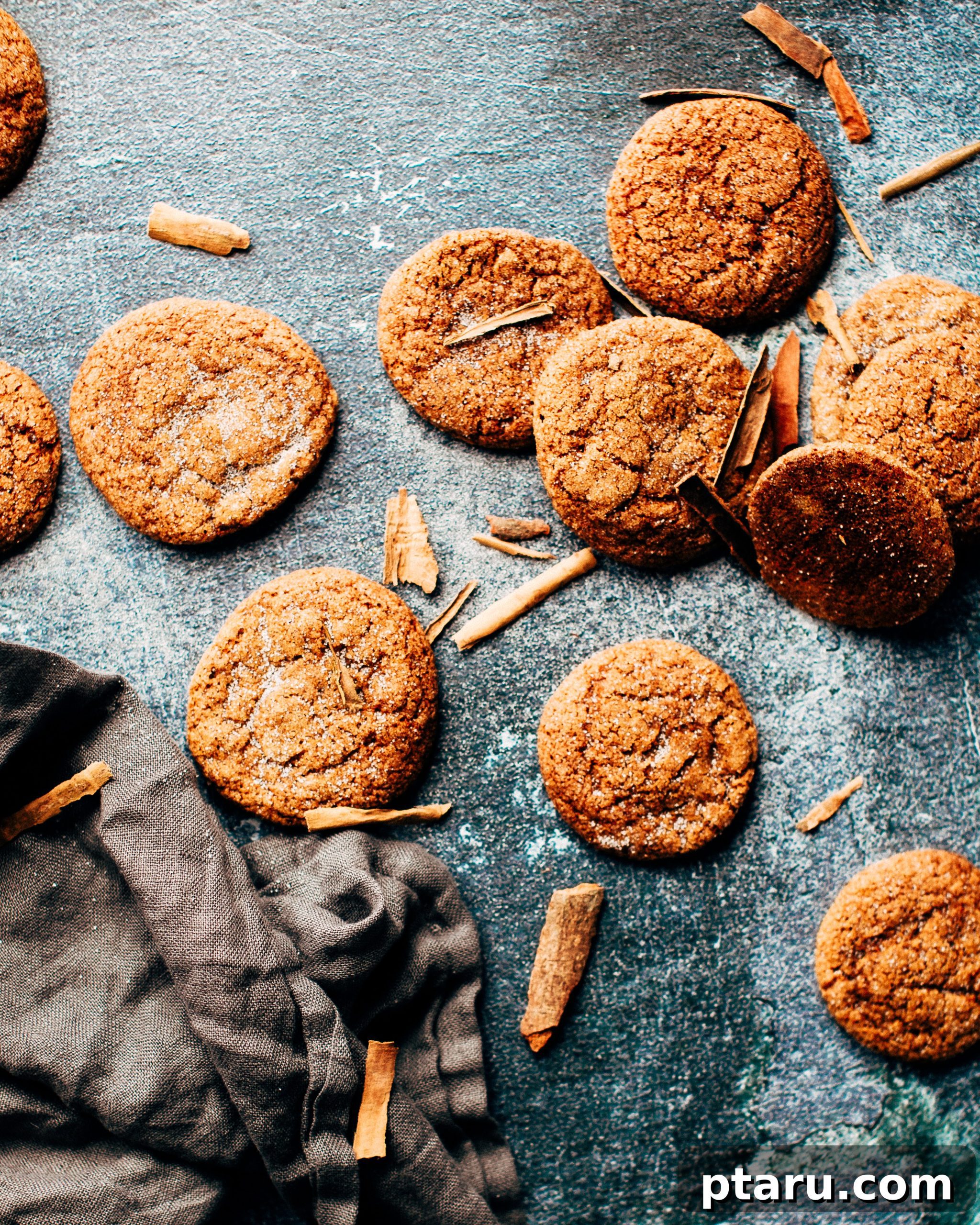 Soft and Chewy Apple-Cinnamon Gingersnaps 3 Close-up of a stack of soft gingersnap cookies, showcasing their crinkled tops and sugar coating, with fresh apples in the background.