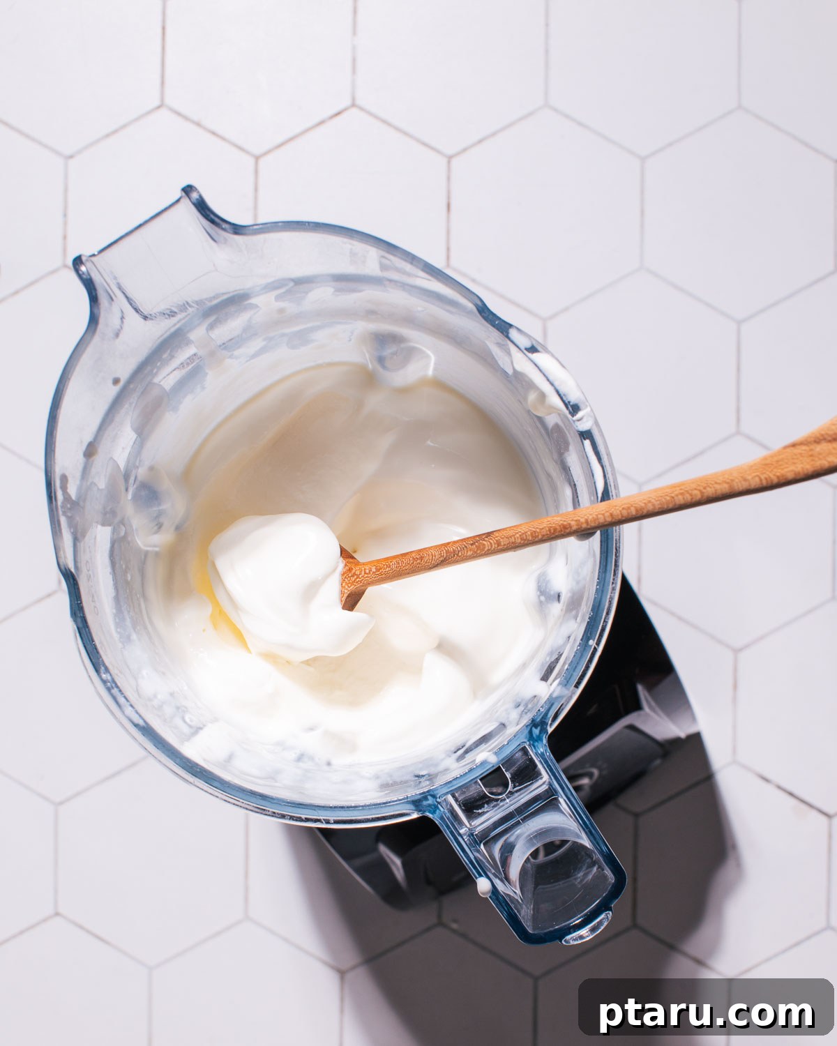 Effortless No-Churn Cookies and Cream Delight 6 Whipped cream in a blender with a spoon.
