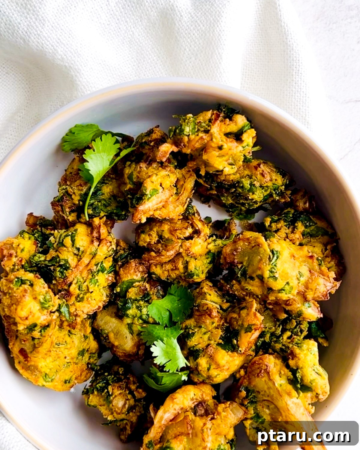 Easy Crispy Indian Pakora 8 A bowl filled with freshly made pakoras, garnished with fresh cilantro, ready to be served.