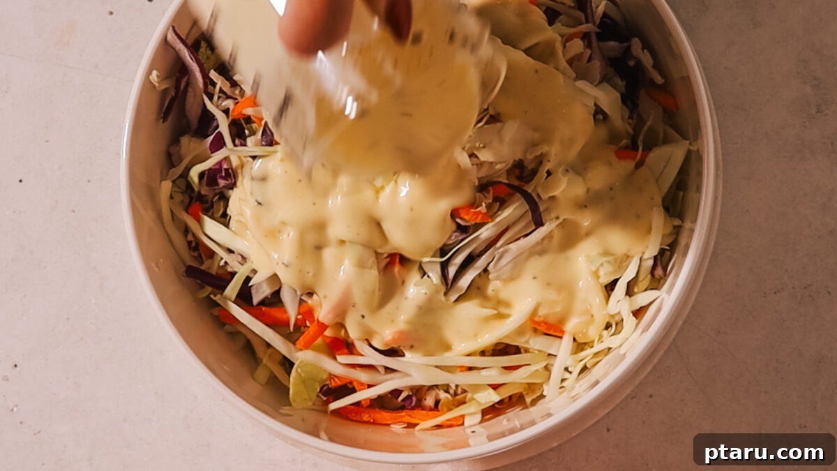 Effortless Classic Coleslaw 5 Pouring the homemade coleslaw dressing over mixed shredded vegetables in a large bowl.