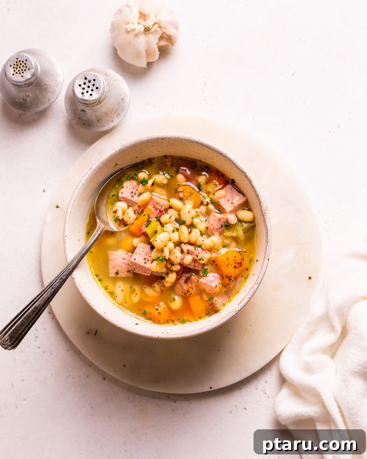 Effortless Ham and Bean Soup: Seriously Delicious and Satisfying 2 A steaming bowl of delicious Ham and Bean Soup, garnished with fresh herbs, with a spoon ready for tasting.