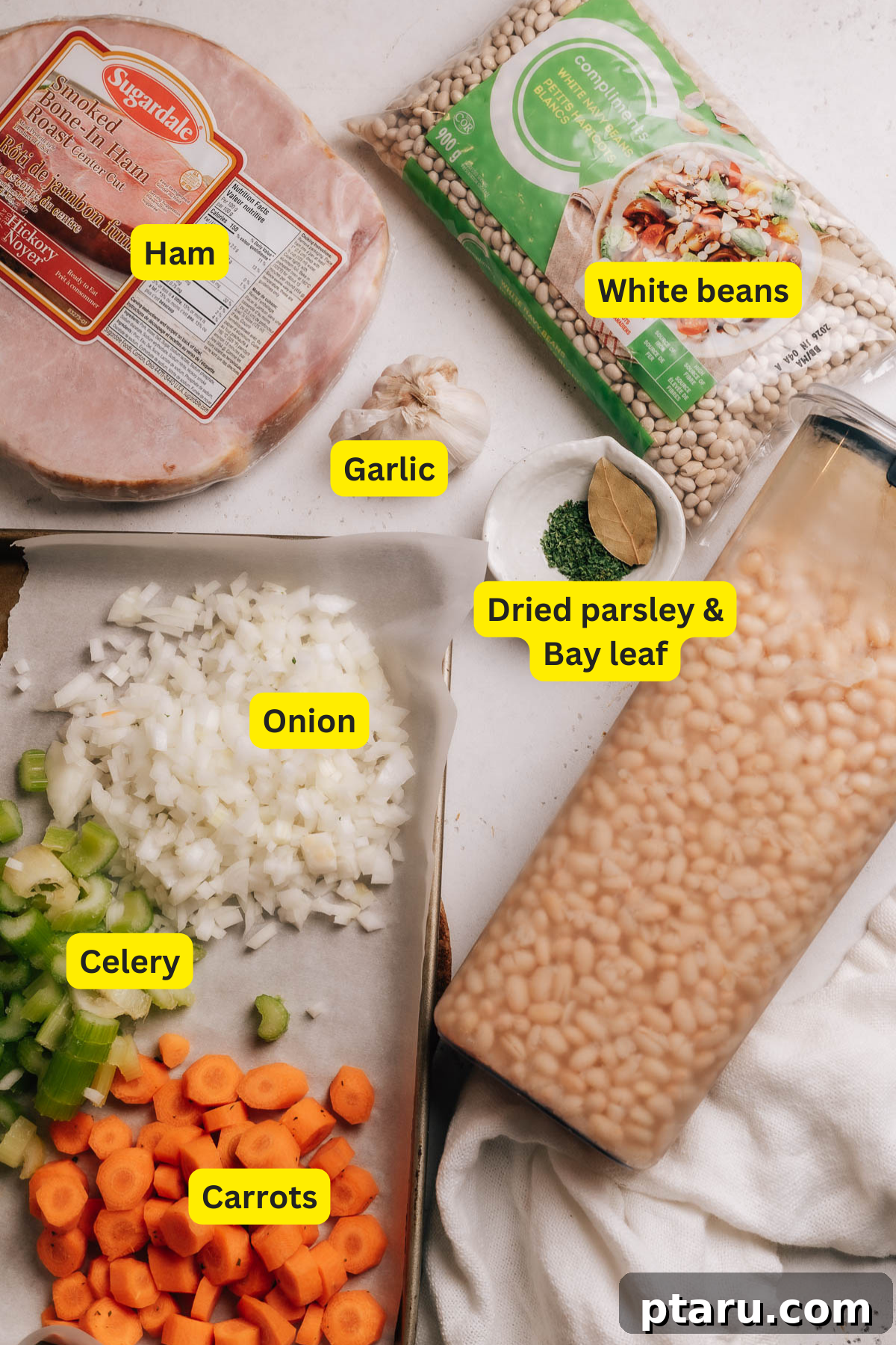 Effortless Ham and Bean Soup: Seriously Delicious and Satisfying 3 A flat lay image showing fresh ingredients for Ham and Bean Soup: diced ham, white beans, carrots, celery, onion, garlic, and chicken broth.