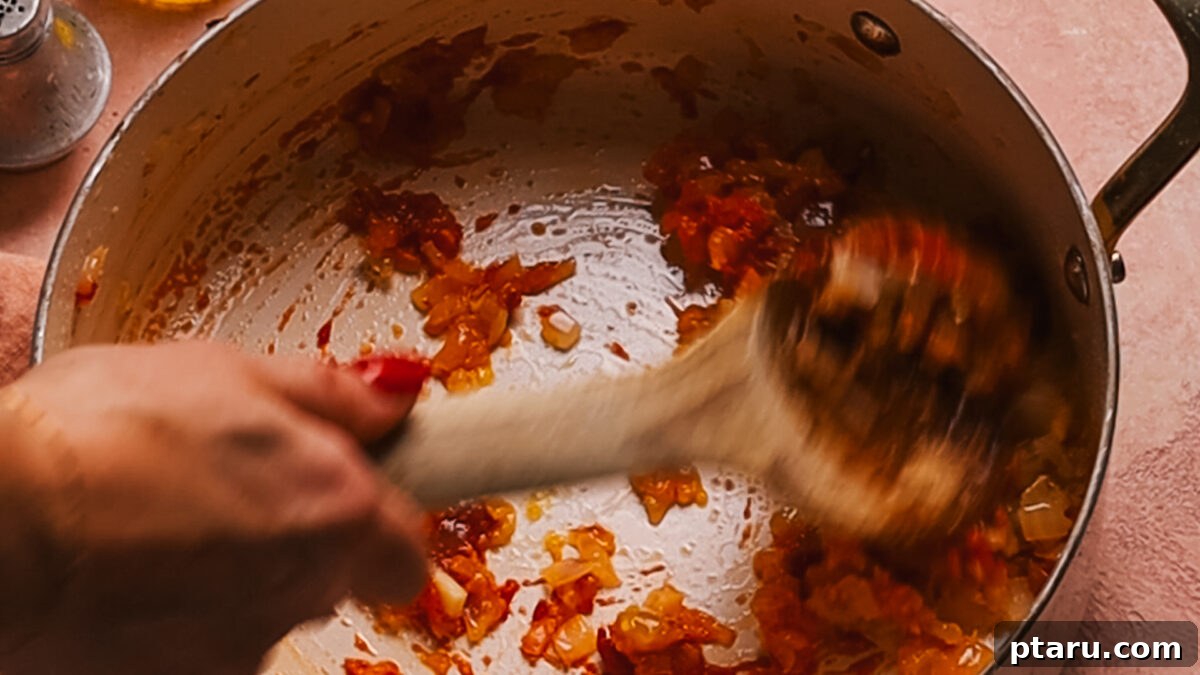 30 Minute One Pot Creamy Tortellini Soup 10 A close-up of tomato paste and bouillon concentrate being toasted in a pot.