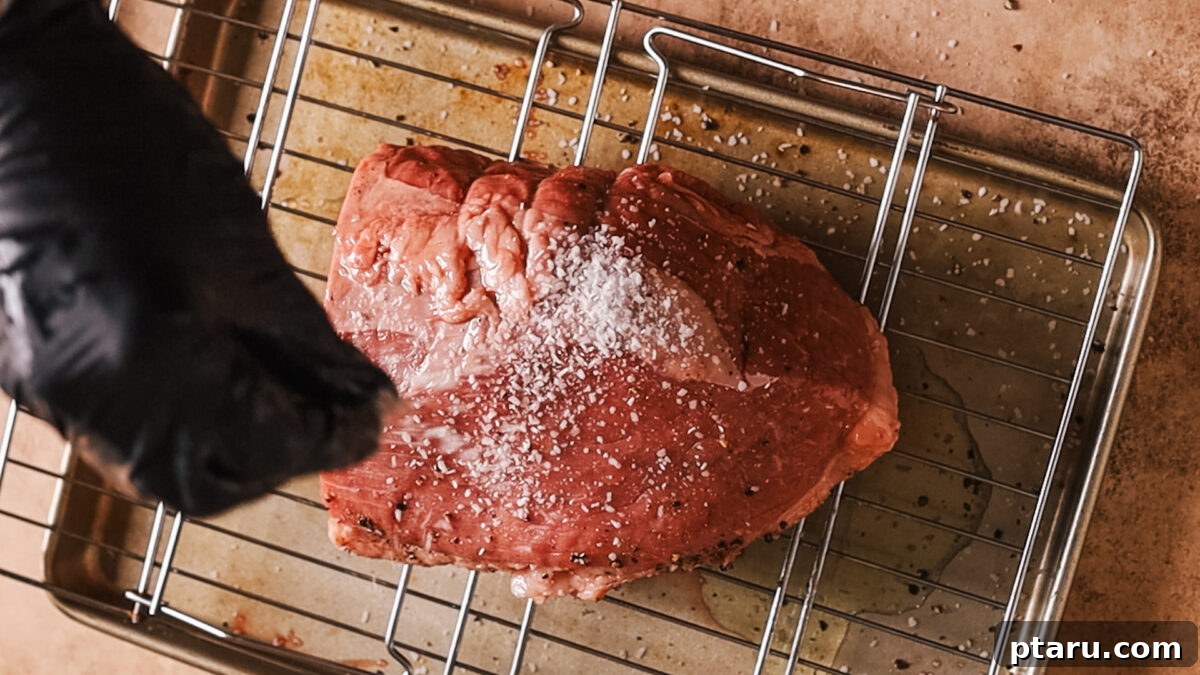 Melt-in-Your-Mouth Eye of Round Roast 4 Applying salt and pepper to the raw eye of round roast.