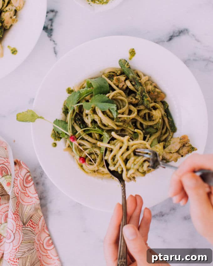 Vibrant Chard Almond Pesto Chicken Fettuccine 5 A vibrant bowl of chicken fettuccine with chard-almond pesto, garnished with fresh herbs and colorful market vegetables.