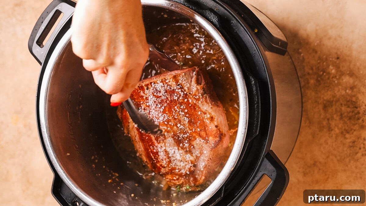 Ultra-Tender Instant Pot Roast Beef 8 Cooked roast beef being removed from the Instant Pot with tongs