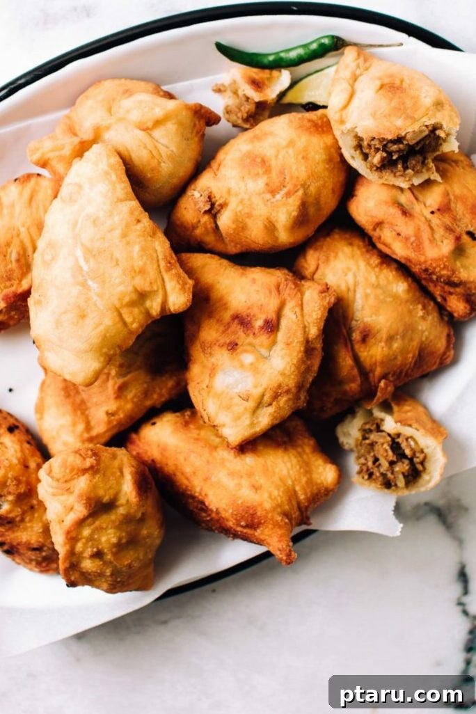 Over 40 Easy Christmas Bites Your Guests Will Devour 23 Chicken Samosas on a plate with one cut open.