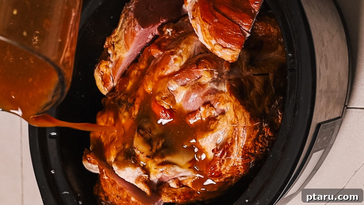 Irresistible Ham Glaze 6 Applying glaze to ham: A basting brush applies the glossy glaze over the scored surface of the ham.
