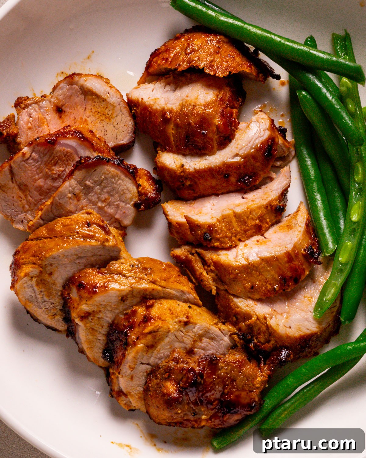 Air Fryer Pork Tenderloin Unbelievably Tender 2 Perfectly cooked air fryer pork tenderloin recipe plated with vibrant green beans, ready to be enjoyed.