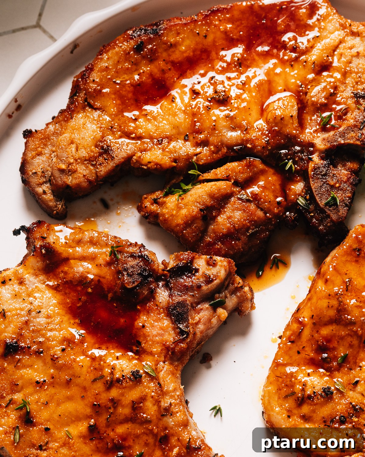 Tender Juicy Air Fryer Pork Chops Guaranteed 10 Close up of air fryer pork chops on a plate with fresh herbs.