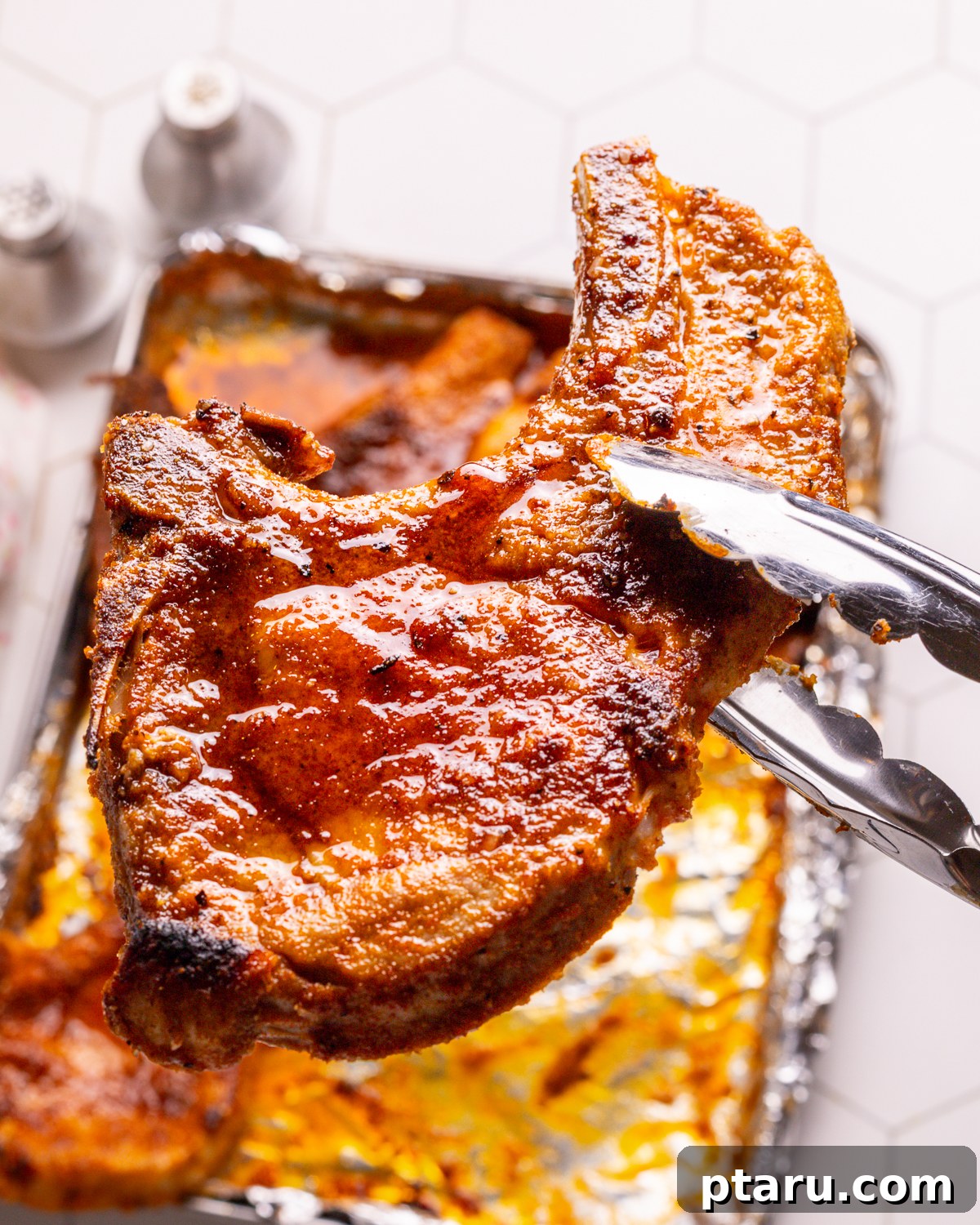 Perfect Oven Baked Pork Chops 7 Step-by-step image of a perfectly baked pork chop held with tongs.