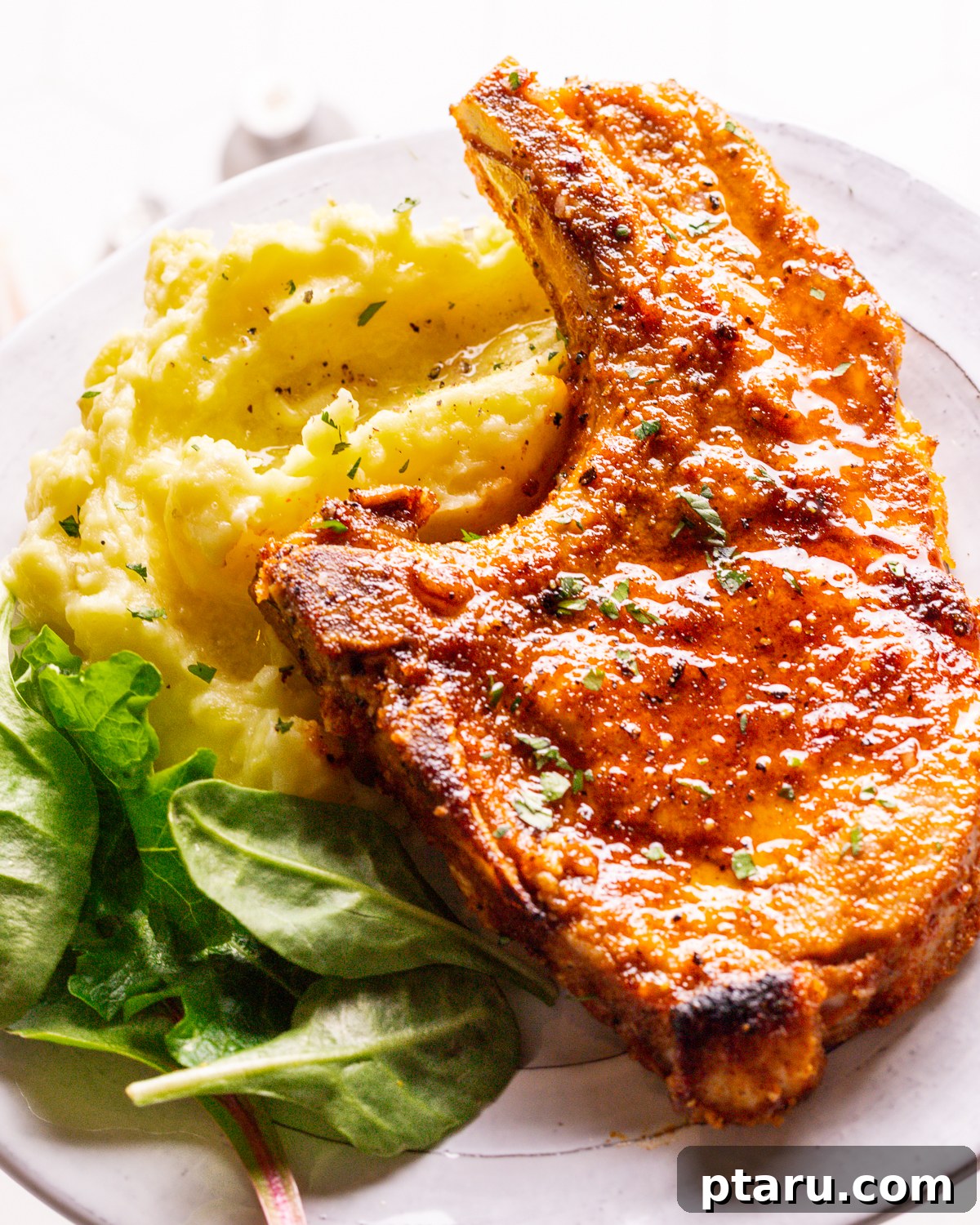 Perfect Oven Baked Pork Chops 8 Baked pork chops served on a plate with mashed potatoes and a fresh green salad.