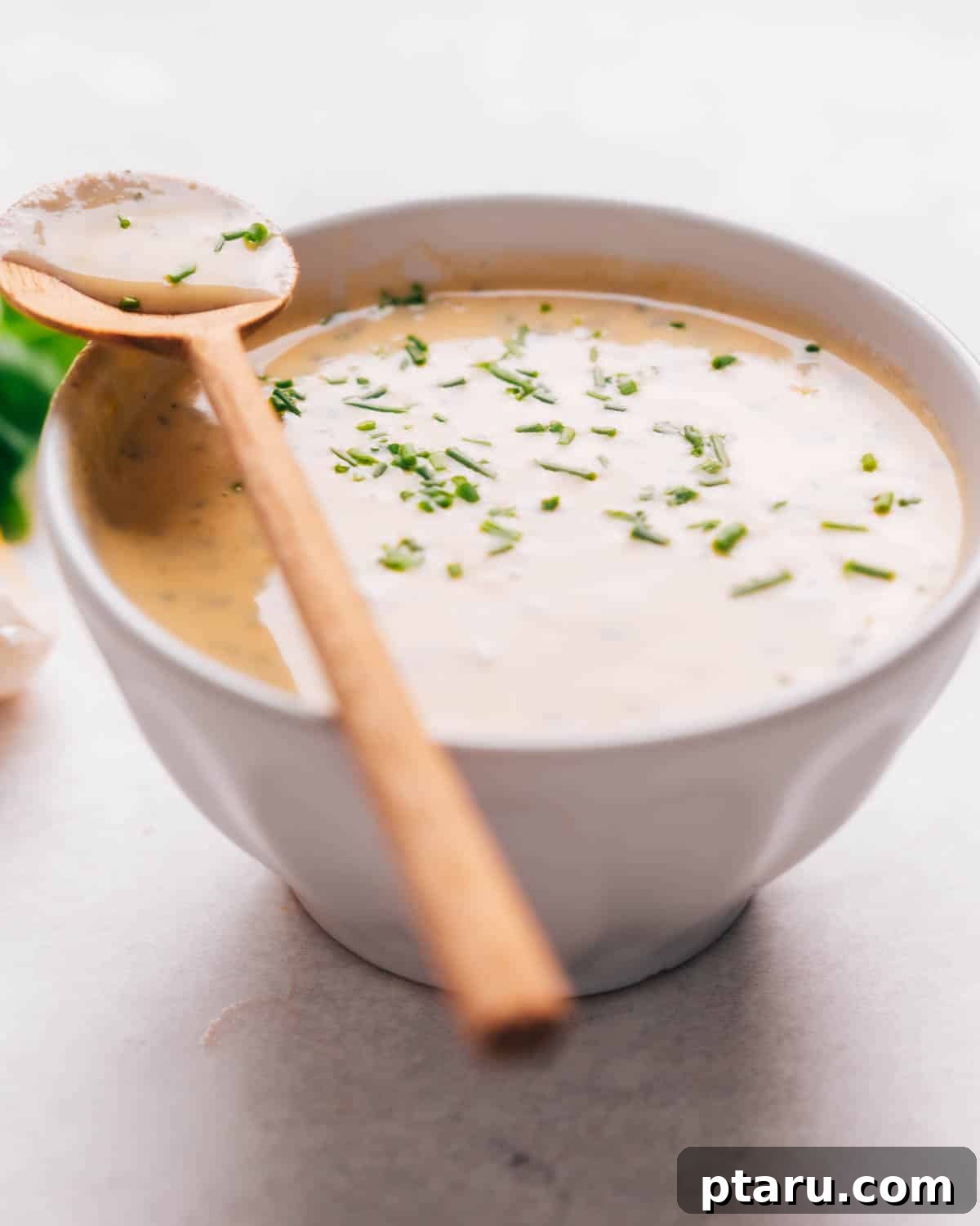 Zesty Lemon Tahini Vinaigrette 4 A close-up shot of creamy lemon tahini dressing in a bowl, garnished with fresh herbs.