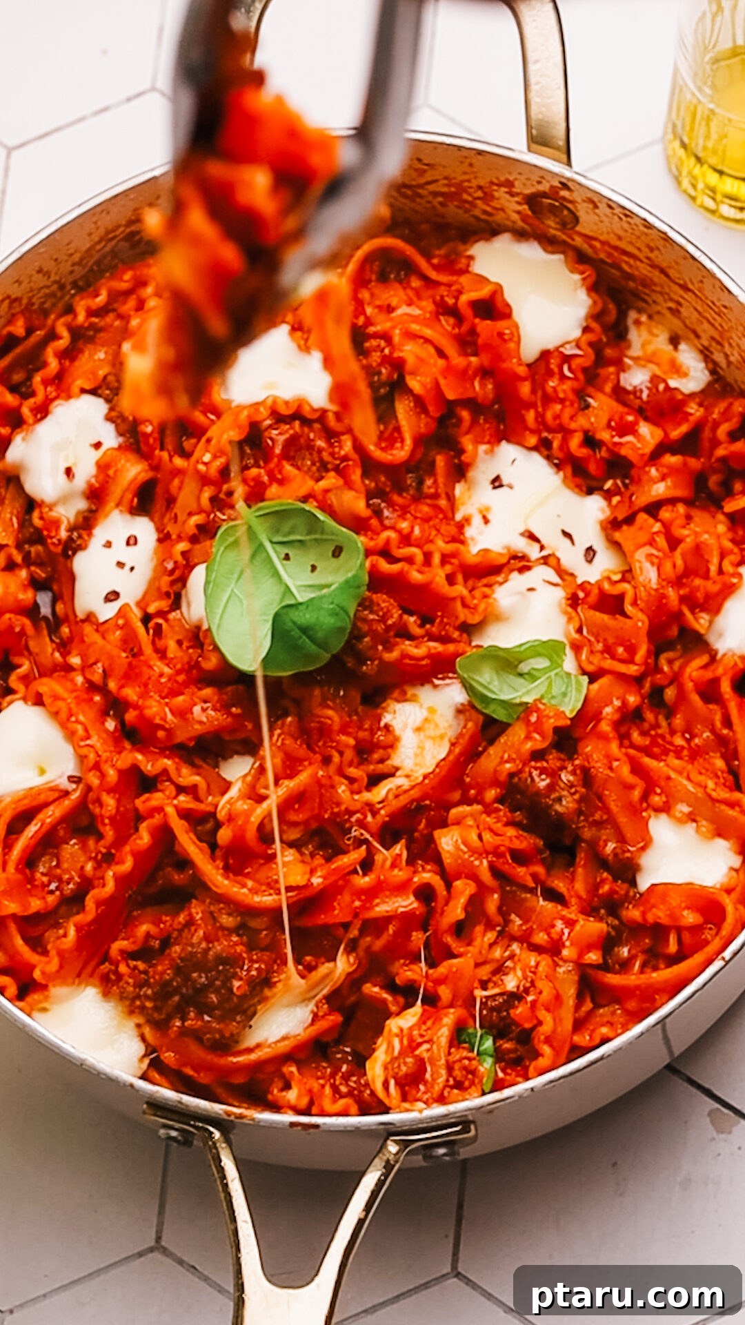 Sauce Simmered Pasta Perfection 12 A generous serving of one-pot pasta with meat sauce in a white bowl, garnished with fresh basil leaves.