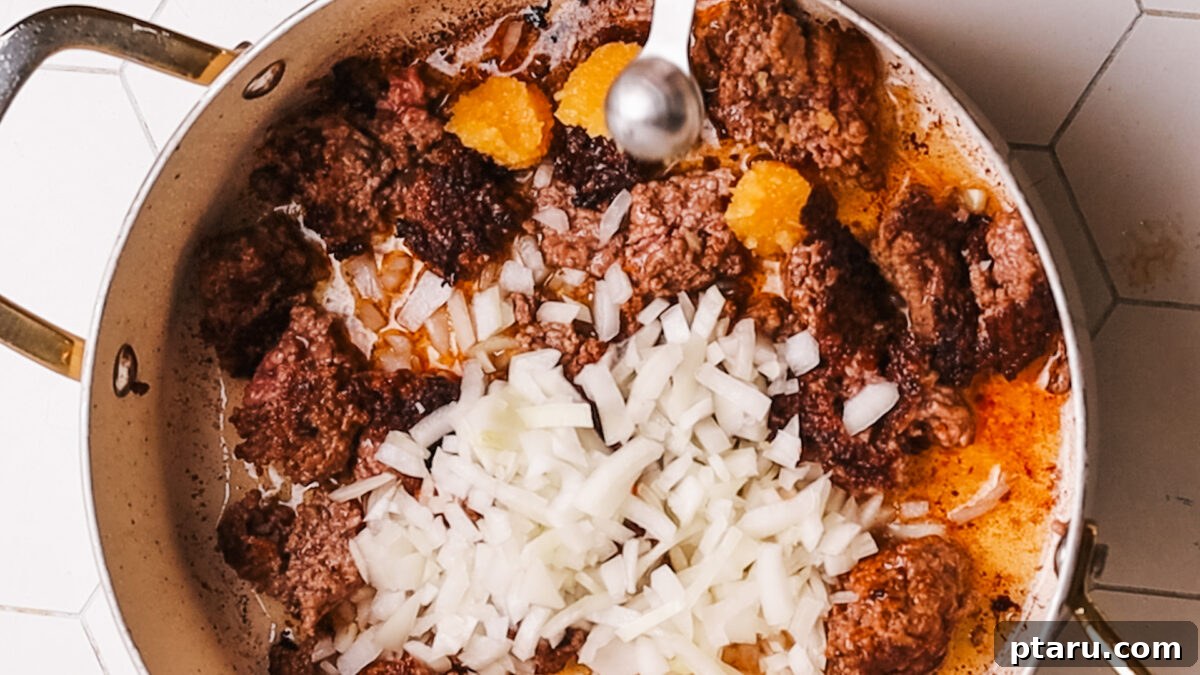 Sauce Simmered Pasta Perfection 6 Chopped onion and seasonings added to the cooked ground beef in a pot.