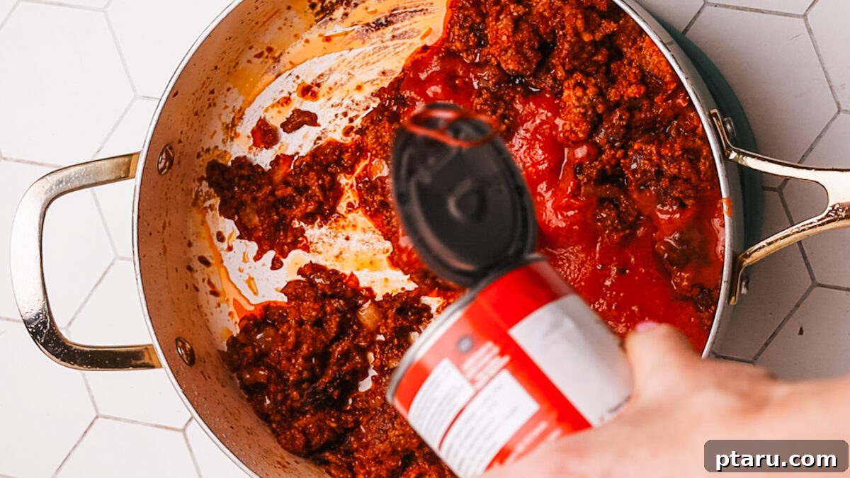 Sauce Simmered Pasta Perfection 8 Tomato paste being stirred into the seasoned ground beef mixture.
