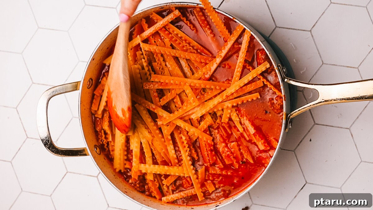 Sauce Simmered Pasta Perfection 10 Dry pasta being added to the simmering meat sauce in a large pot.