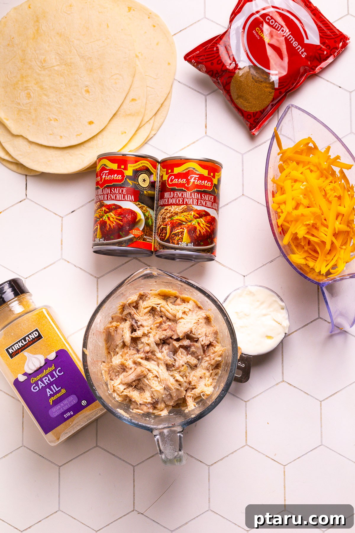 Cheesy Chicken Enchilada Bake 3 A selection of fresh ingredients laid out for making Chicken Enchilada Casserole, including shredded chicken, tortillas, cheese, and sauce.