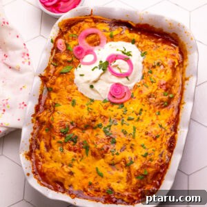 Chicken enchilada casserole, golden and bubbly, with a topping of sour cream and pickled onions.