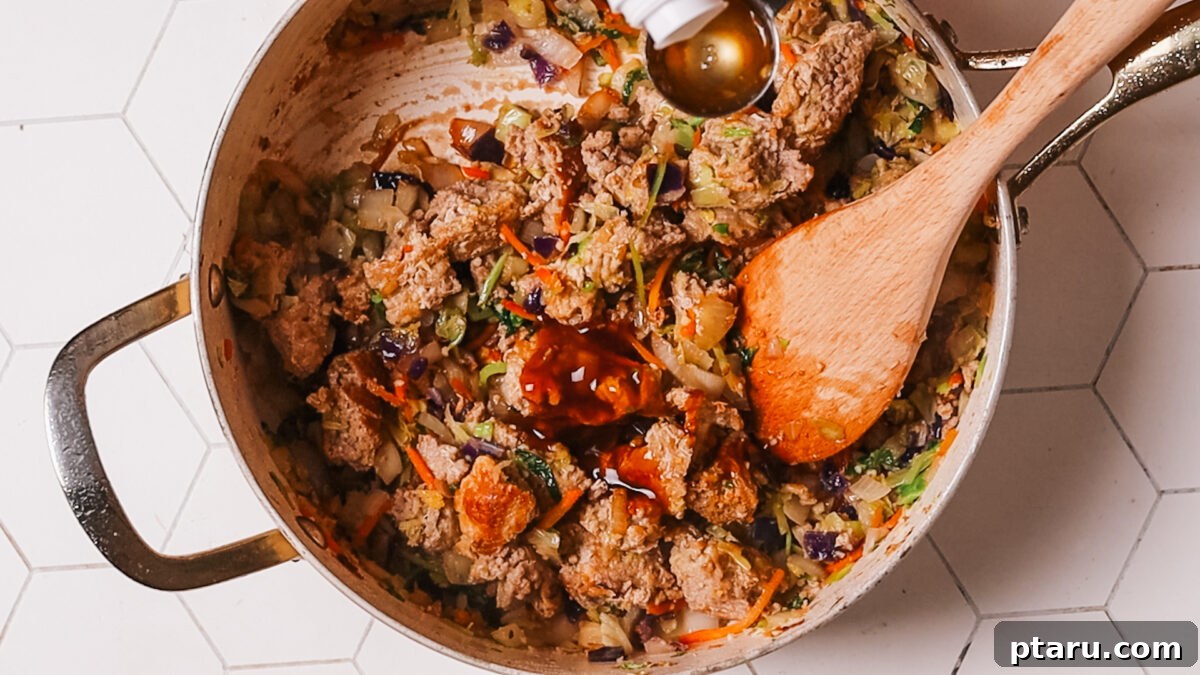 Quick Fix Egg Roll Bowl 9 Stirring in soy sauce, rice vinegar, and oyster sauce to coat all ingredients evenly.