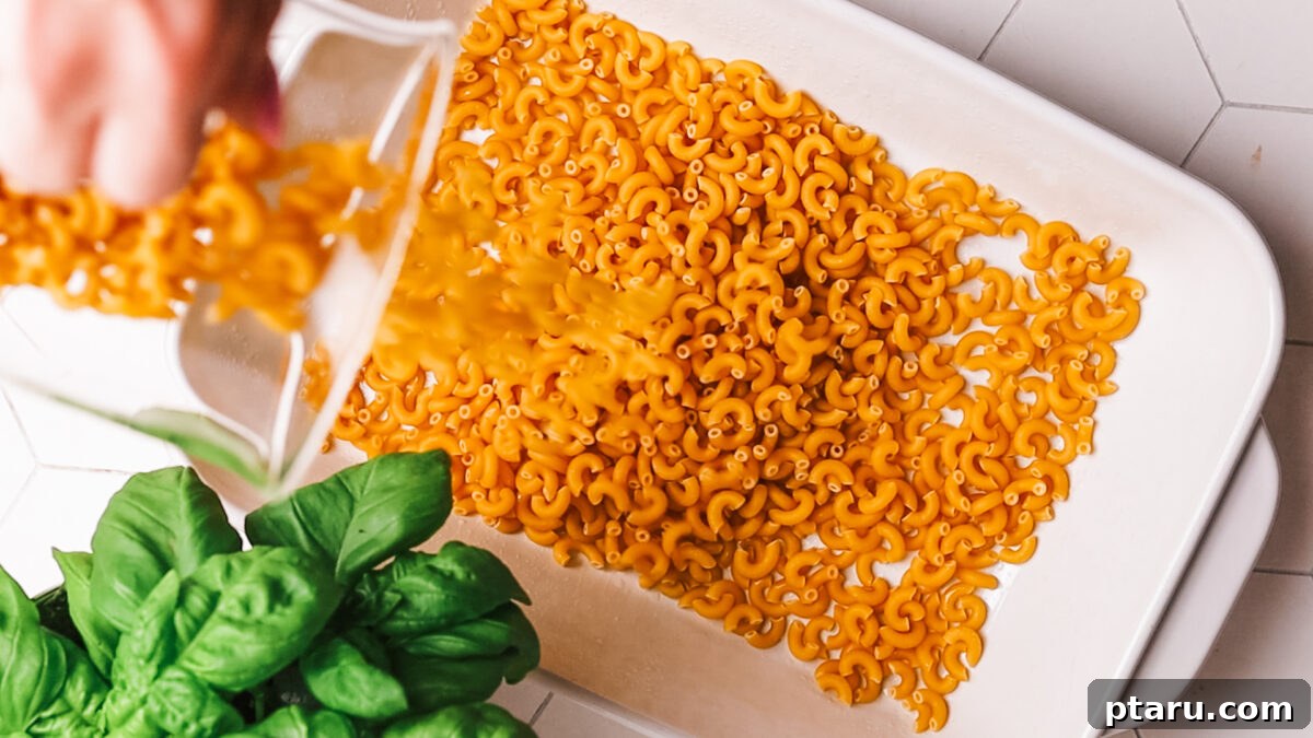 Classic Comfort Hamburger Bake 4 Uncooked short pasta being evenly spread at the bottom of a 9x13-inch baking dish.