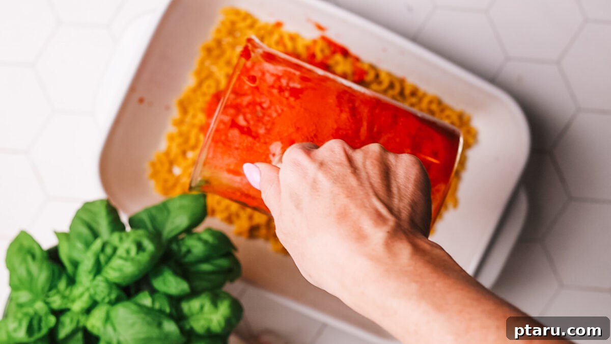 Classic Comfort Hamburger Bake 5 Marinara sauce and boiling water being poured over the uncooked pasta in the baking dish.